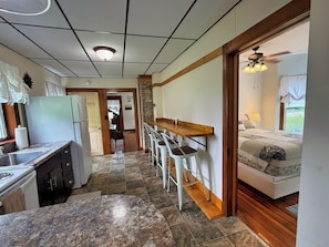 A compact kitchen with a refrigerator, sink, and a dining area with stools.