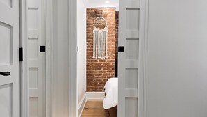 A hallway with wooden flooring, white walls, and a macramé wall hanging. - Catskill Ski Hike Lake Pet Main St Pool (Catskill)