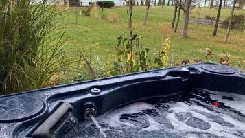 Un bain à remous avec vue sur une zone herbeuse et des arbres.