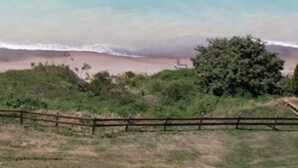 Blick auf die Küste mit Strand und einem Holzzaun im Vordergrund.