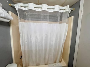 A bathroom with a shower curtain, a towel rack, and a toilet. - Economy Inn Sweetwater I-75 (Sweetwater)