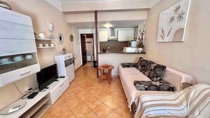 A modern living room with a sofa, TV, and a small dining table. - Holiday apartment with terrace and air conditioning (Dramalj)