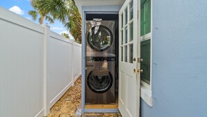 A laundry room with two stacked washers and dryers, a white door, and a blue wall.