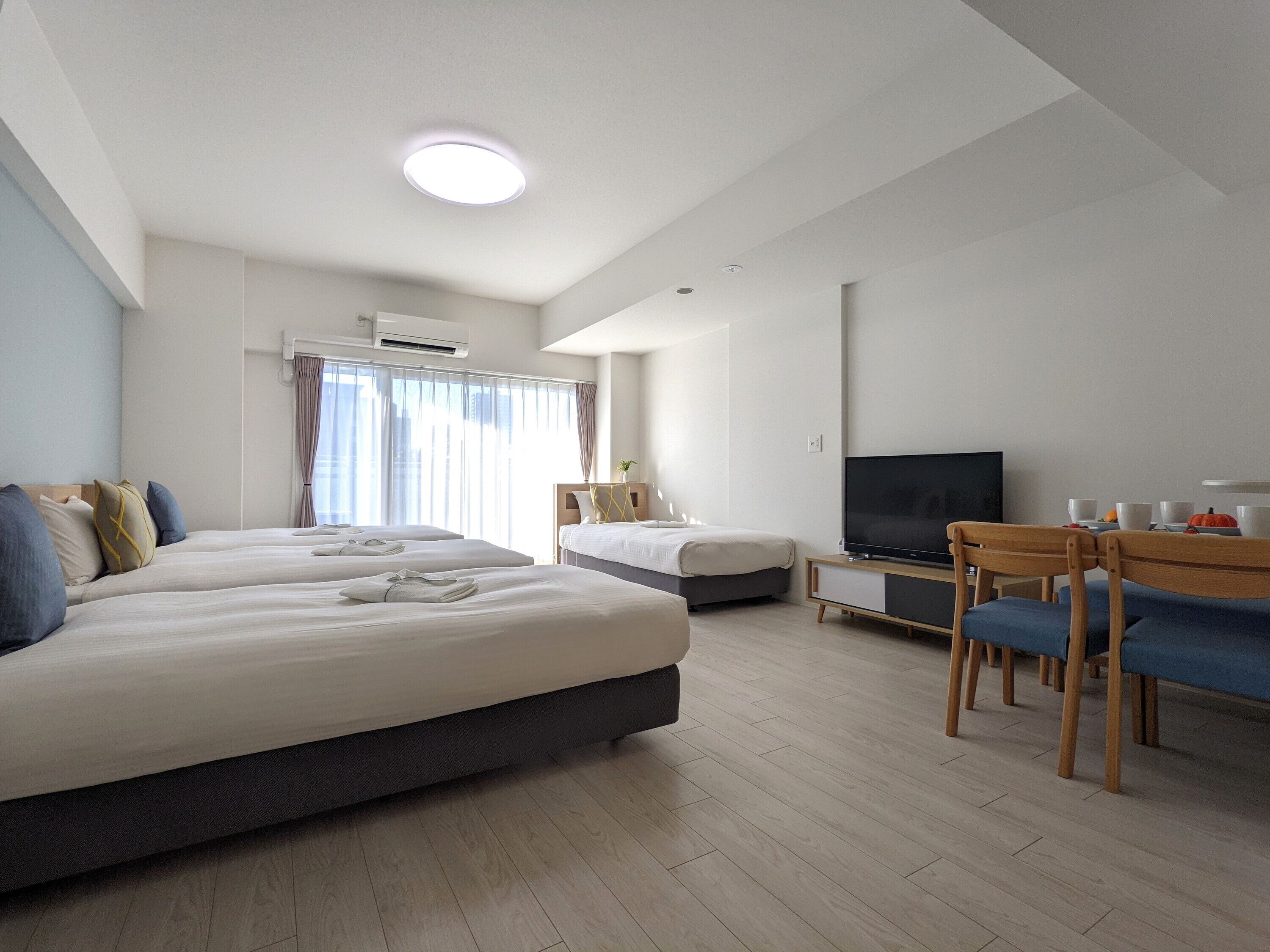 A hotel room with two beds, a television, a desk, and a chair.