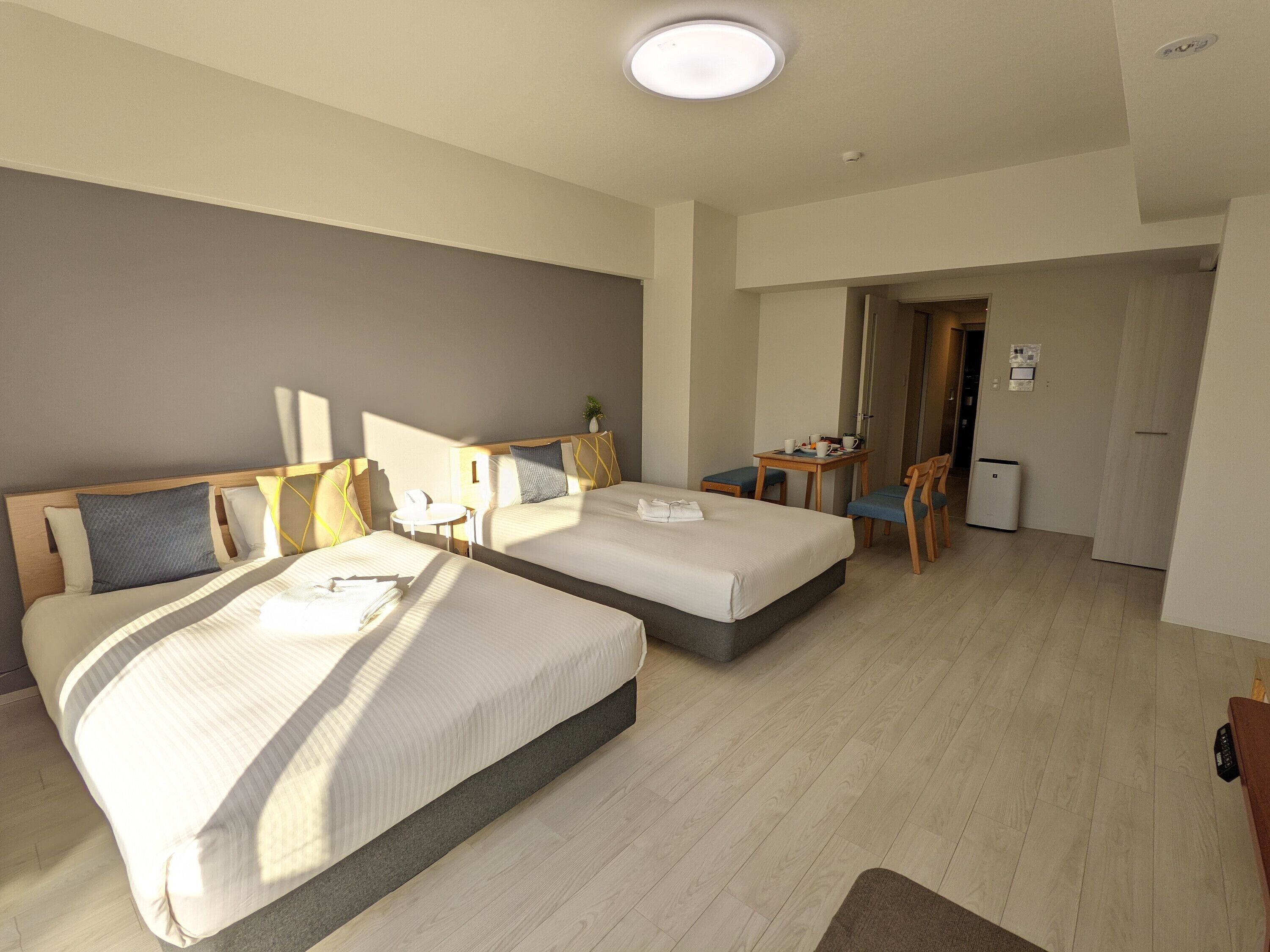 Una habitación de hotel con dos camas, una mesita, sillas y un escritorio.