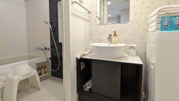 A bathroom with a bathtub, a sink with a mirror above it, and a shower area.