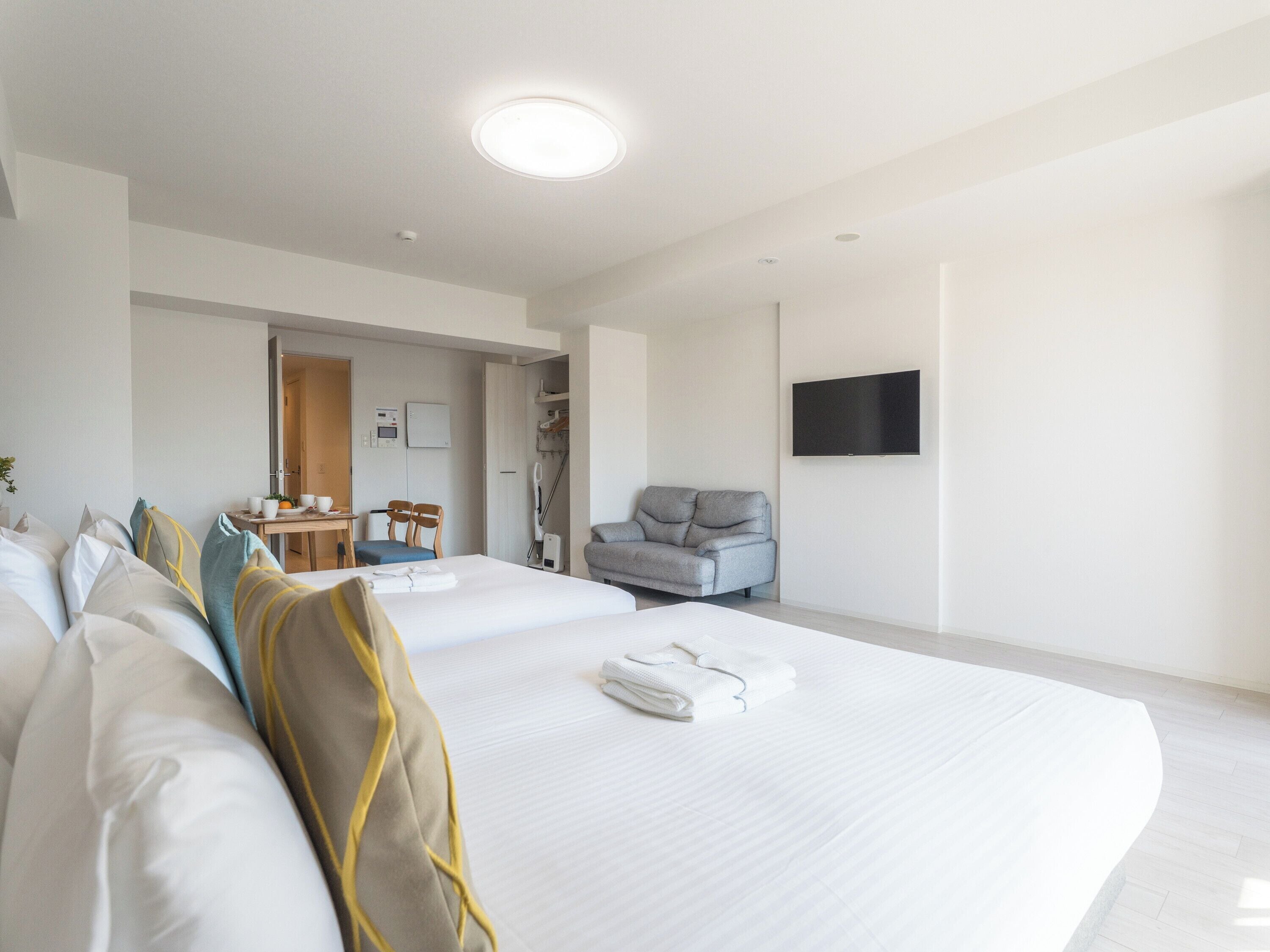 Habitación de hotel con dos camas, un escritorio, sillas, televisión y baño.