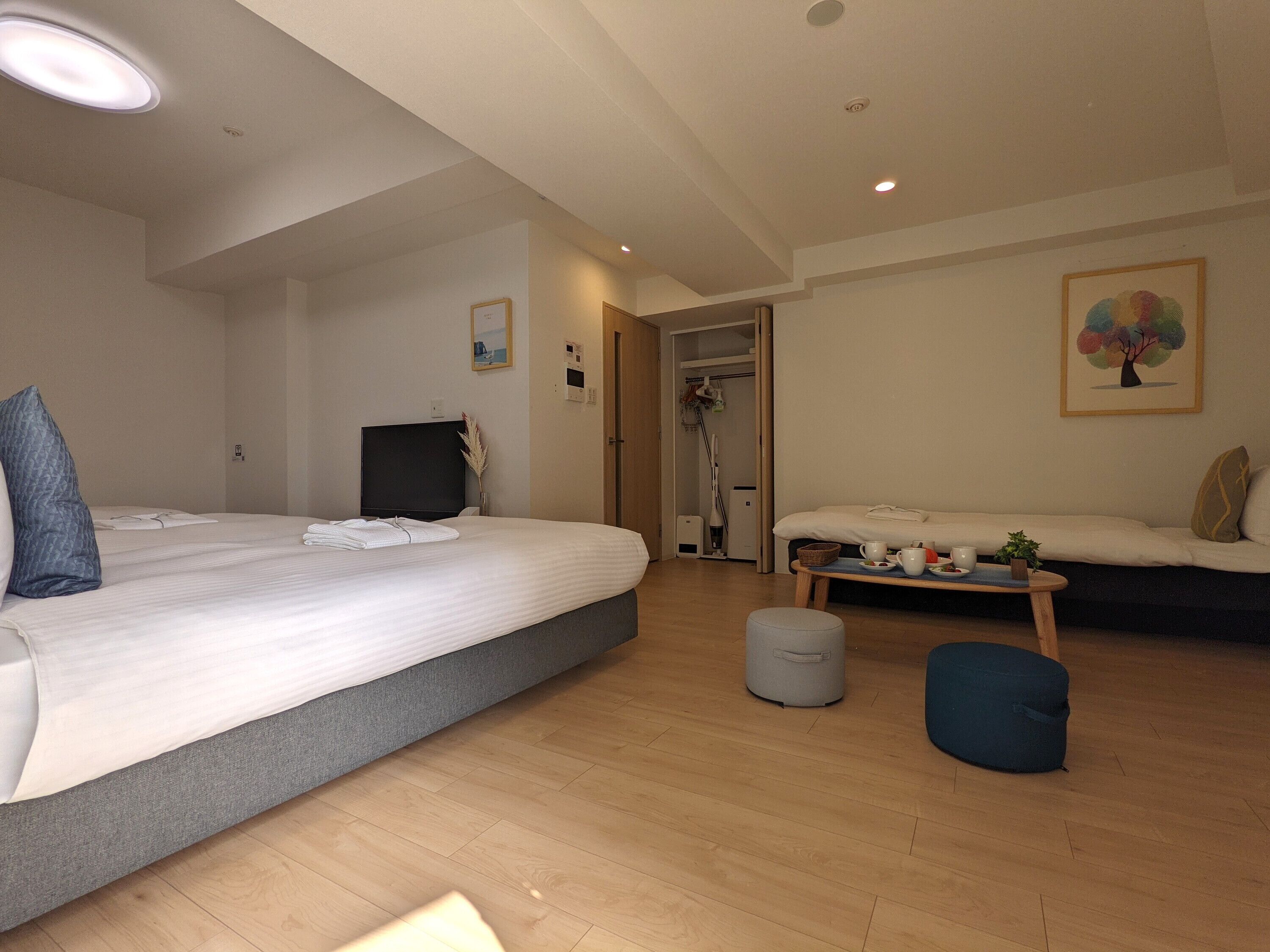 Et hotelværelse med en stor seng, en mindre sofa, et sengebord og et fjernsyn.