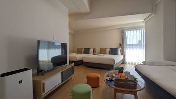 A modern hotel room with a flat-screen TV, a sofa, a bed with multiple pillows, a small table with a basket, and a window with curtains.