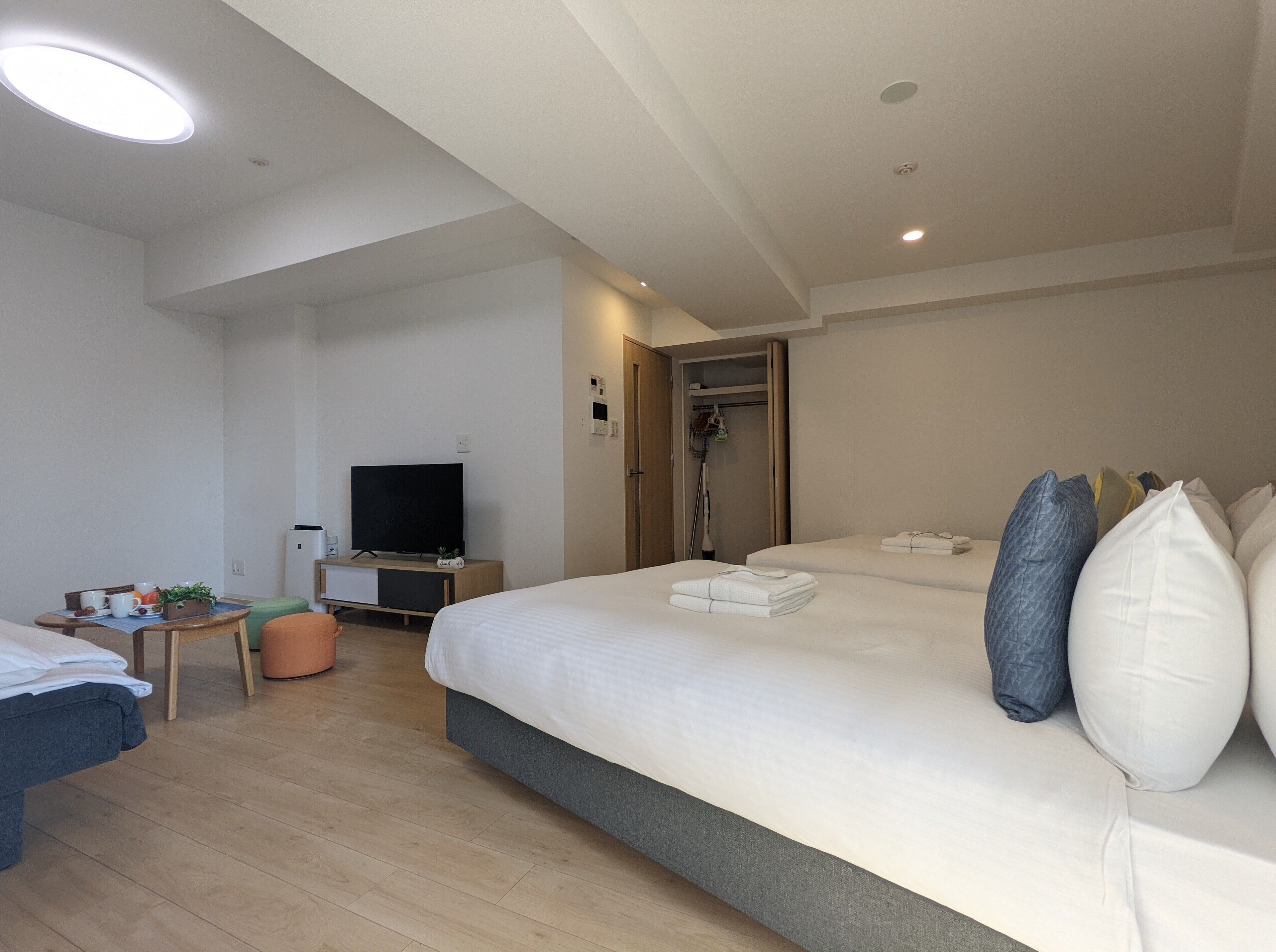 A modern hotel room with a large bed, a TV, a desk, and a shower area.
