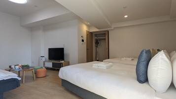 A modern hotel room with a large bed, a TV, a desk, and a shower area.