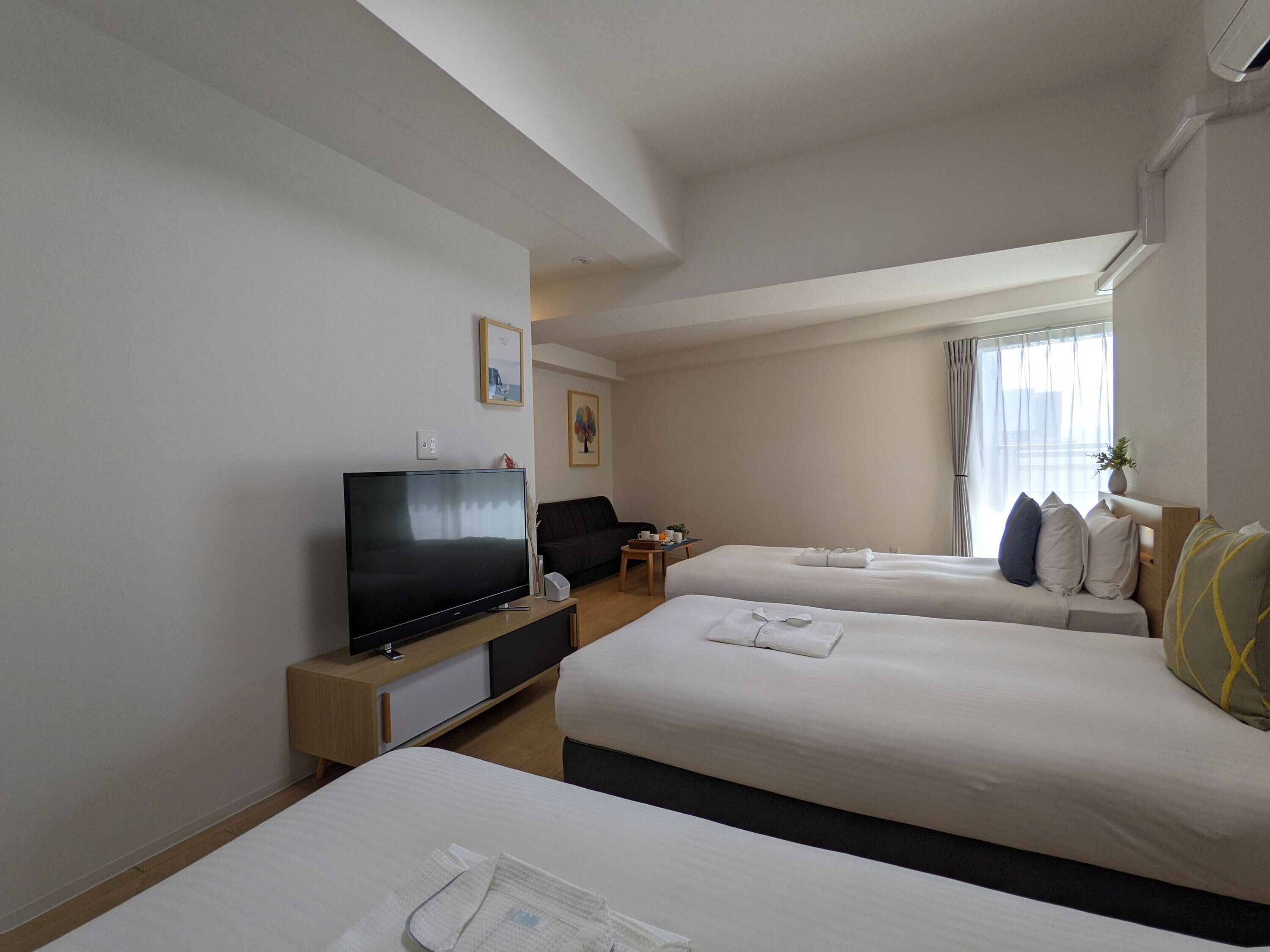 Een hotelkamer met twee bedden, een televisie, een bureau en een raam met gordijnen.
