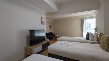 Een hotelkamer met twee bedden, een televisie, een bureau en een raam met gordijnen.