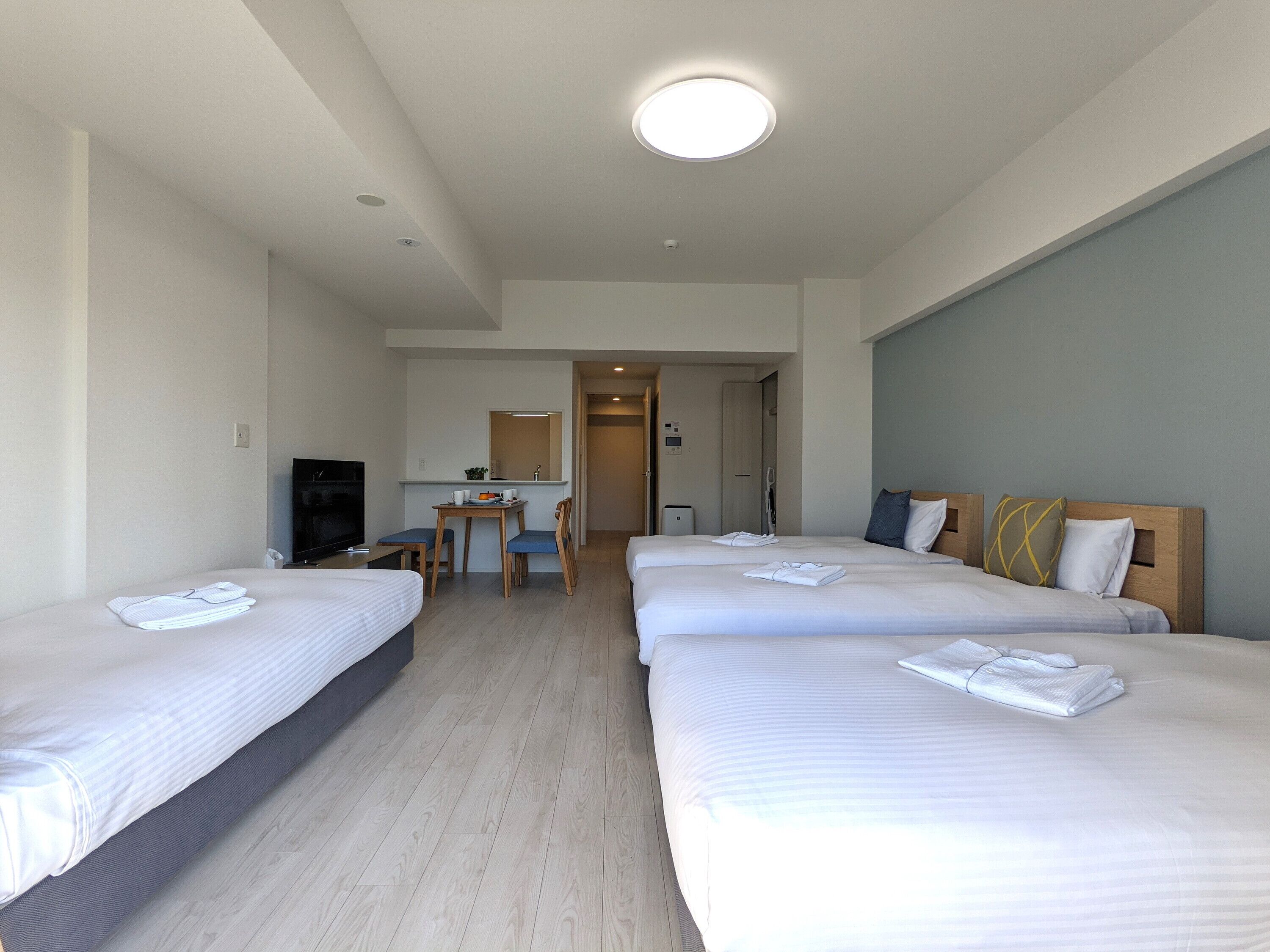 Habitación de hotel con tres camas, un escritorio y una televisión.