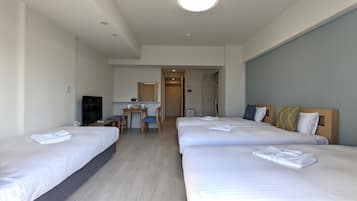 Habitación de hotel con tres camas, un escritorio y una televisión.