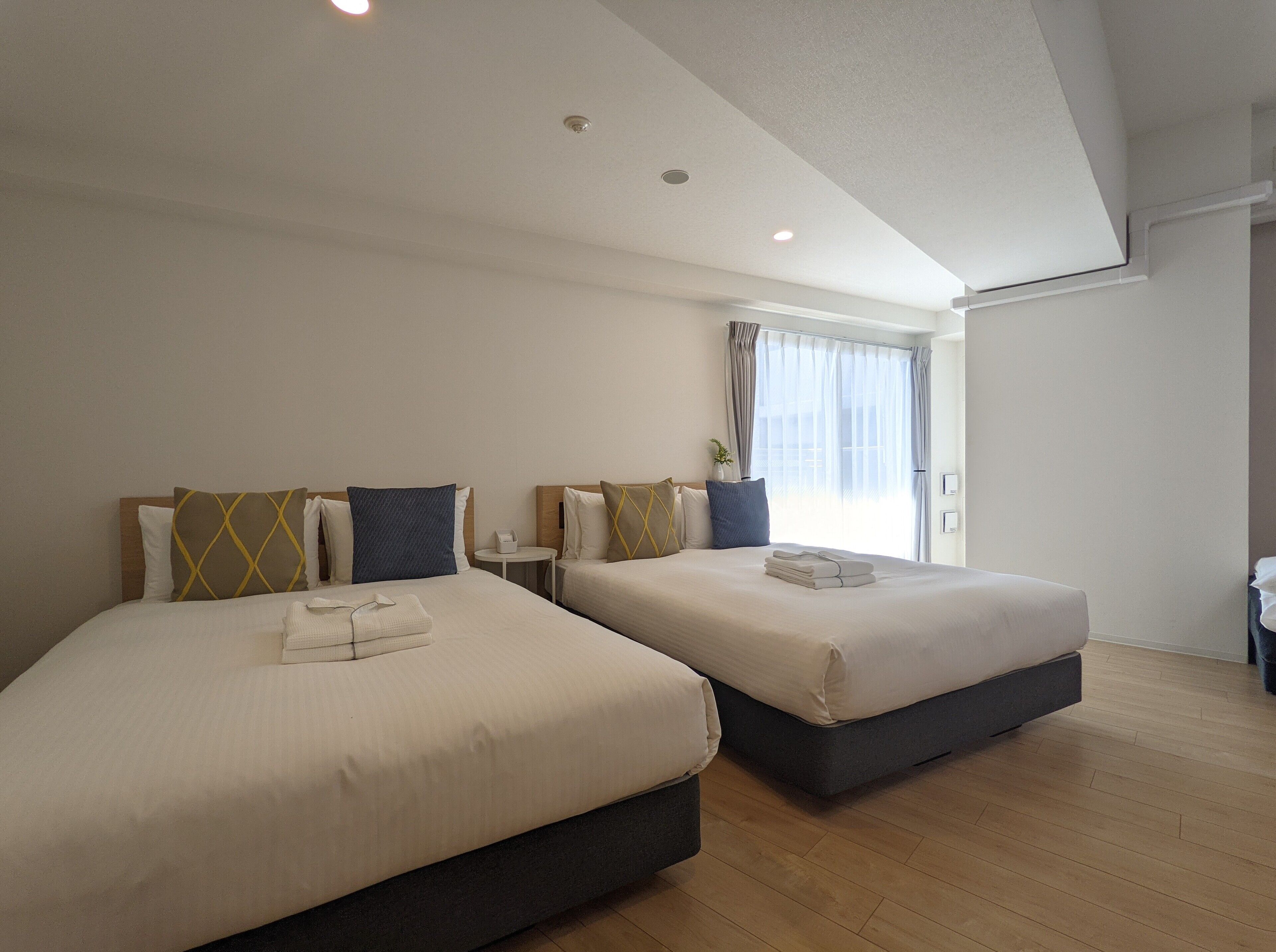 A hotel room with two beds, a small round table, and a window with curtains.