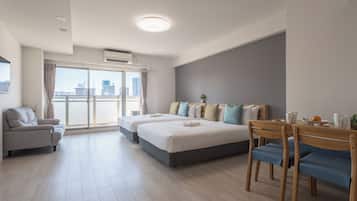 Quarto de hotel moderno com varanda, área de refeições e uma cama grande com várias almofadas.