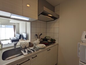 A modern kitchen with a built-in oven, a sink, and a dining area with a sofa and table. - ESLEAD HOTEL OSAKA TSURUHASHI (Osaka)