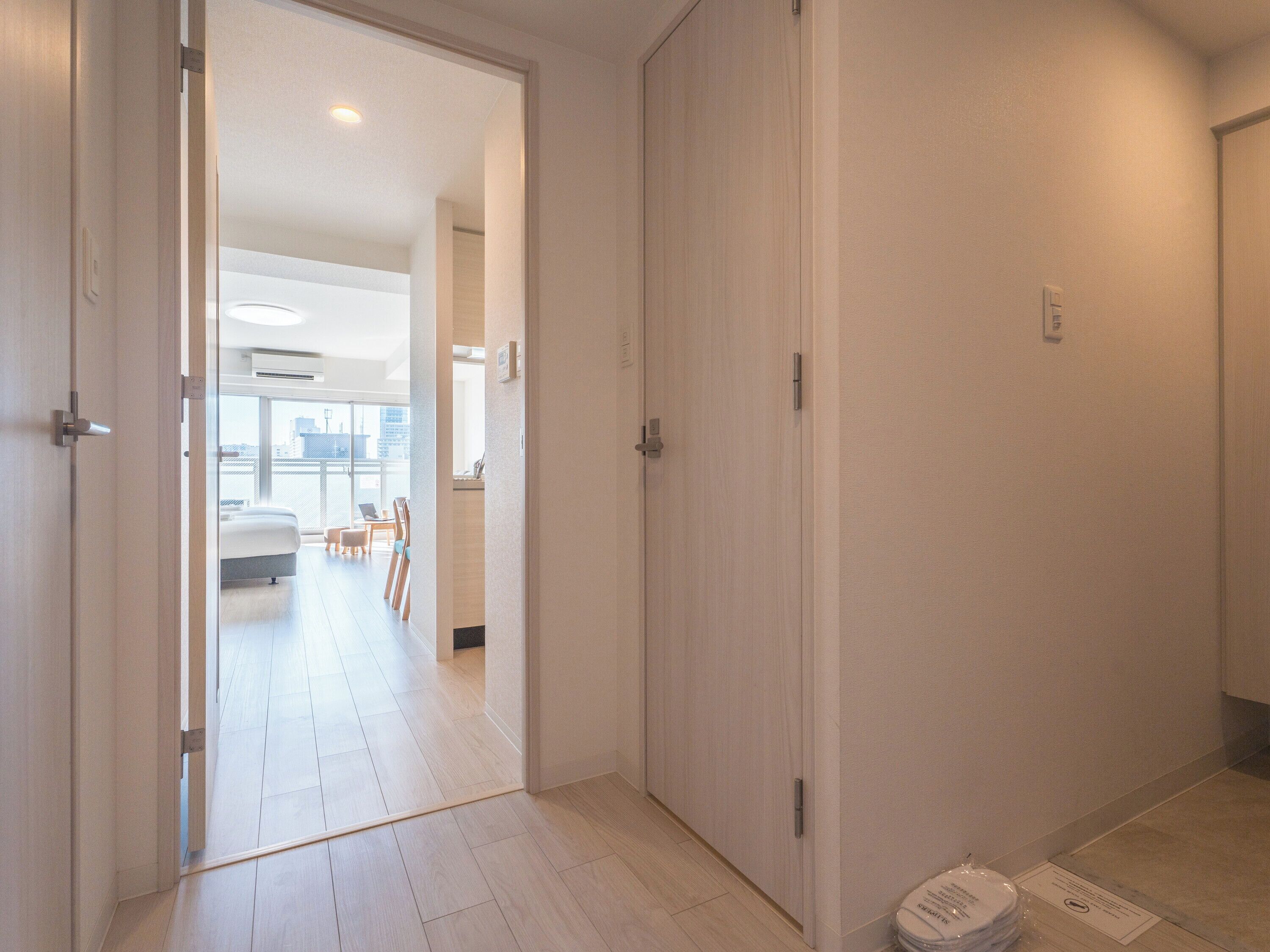 A hallway with a sliding door leading to a bedroom with a bed and a desk.