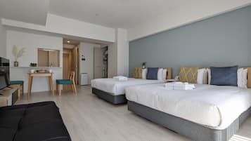 A modern hotel room with two beds, a desk, and a seating area.