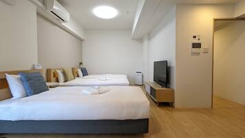 A hotel room with two beds, a TV, and a small desk.