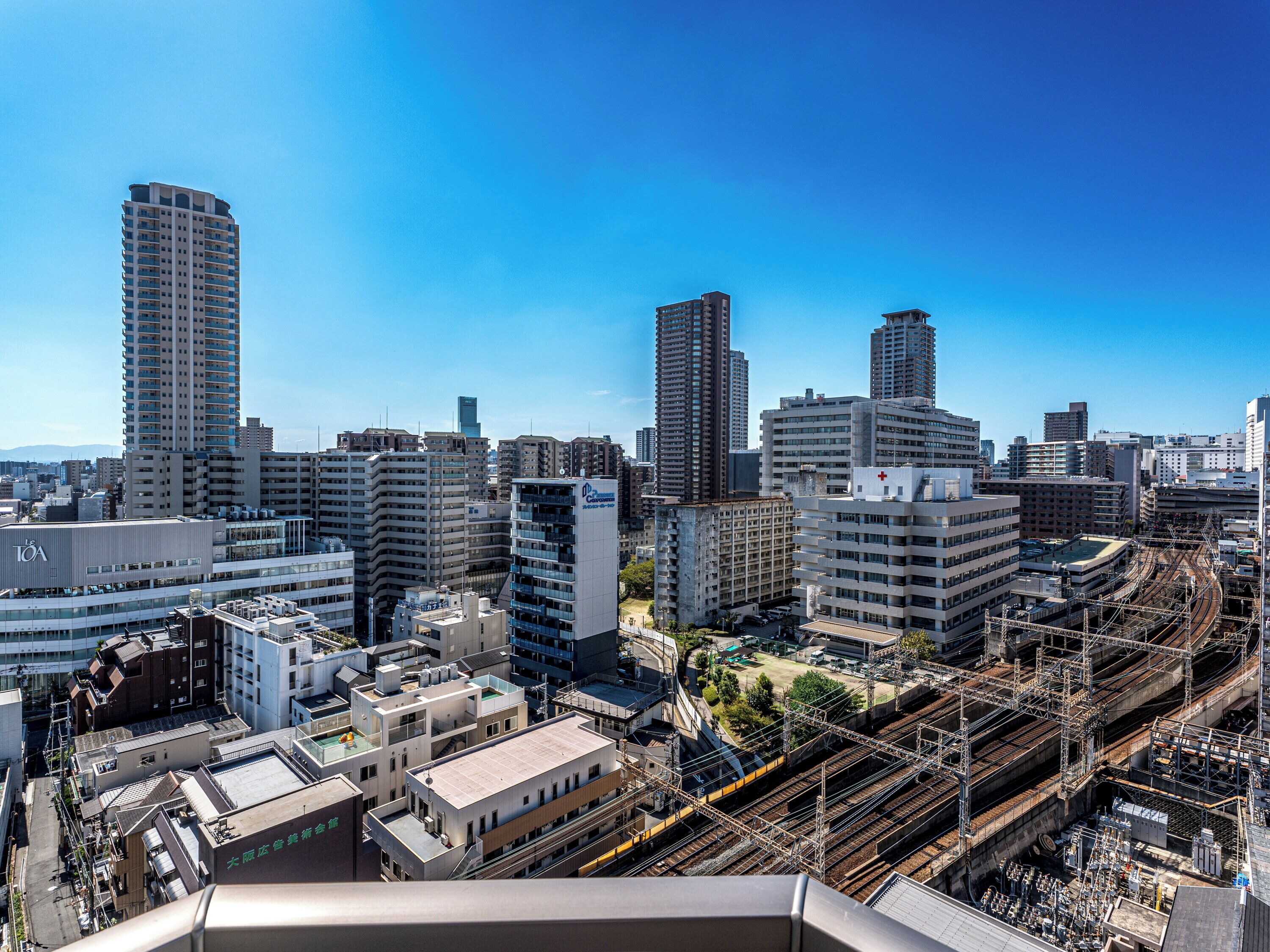 A cityscape with high-rise buildings, a train station, and a hospital.