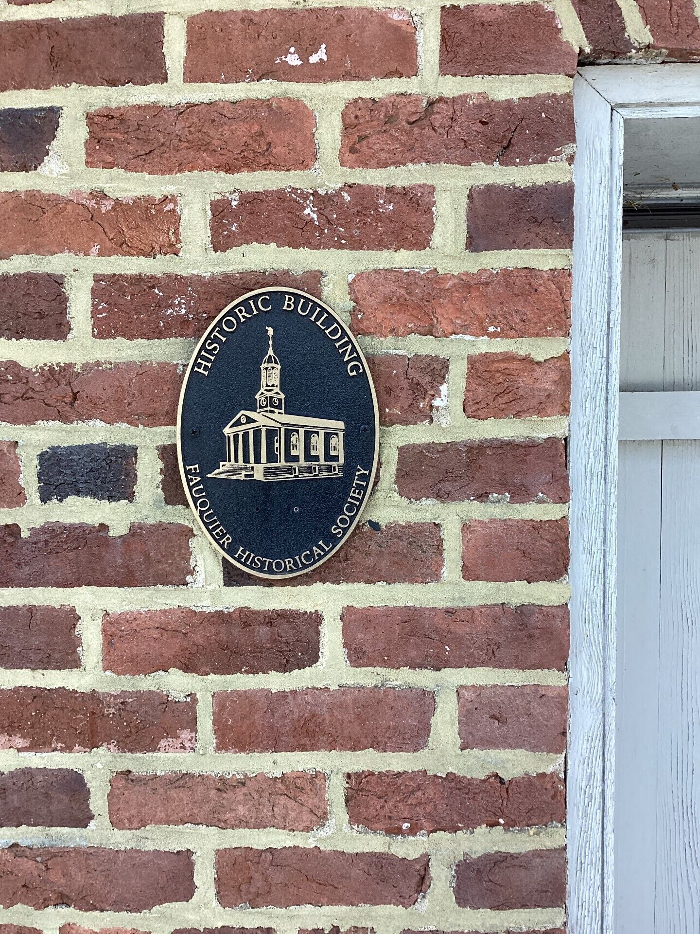 Een bakstenen muur met een ronde plaquette waarop staat: 'Historic Building' en 'Fauquier Historical Society'.