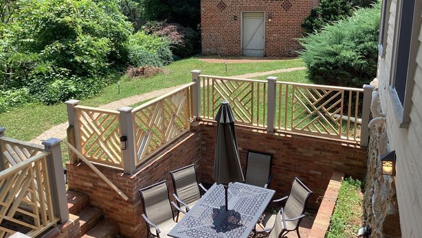 A patio area with a table and chairs, a small brick building in the background, and a wooden fence.