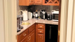 A compact kitchen with wooden cabinets, a dishwasher, a coffee maker, and a microwave.