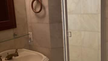 A bathroom with a sink, mirror, and a glass-enclosed shower.