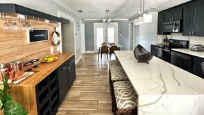 A modern kitchen with a marble island, wooden cabinetry, and a welcome sign. - Modern Peaceful Pool Home, 25 Mins To Theme Parks! (St. Cloud)