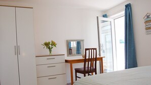 A bedroom with a bed, a desk, a chair, a wardrobe, and a window with curtains. - Sunny Side Up Beach House in Tywyn (Tywyn)