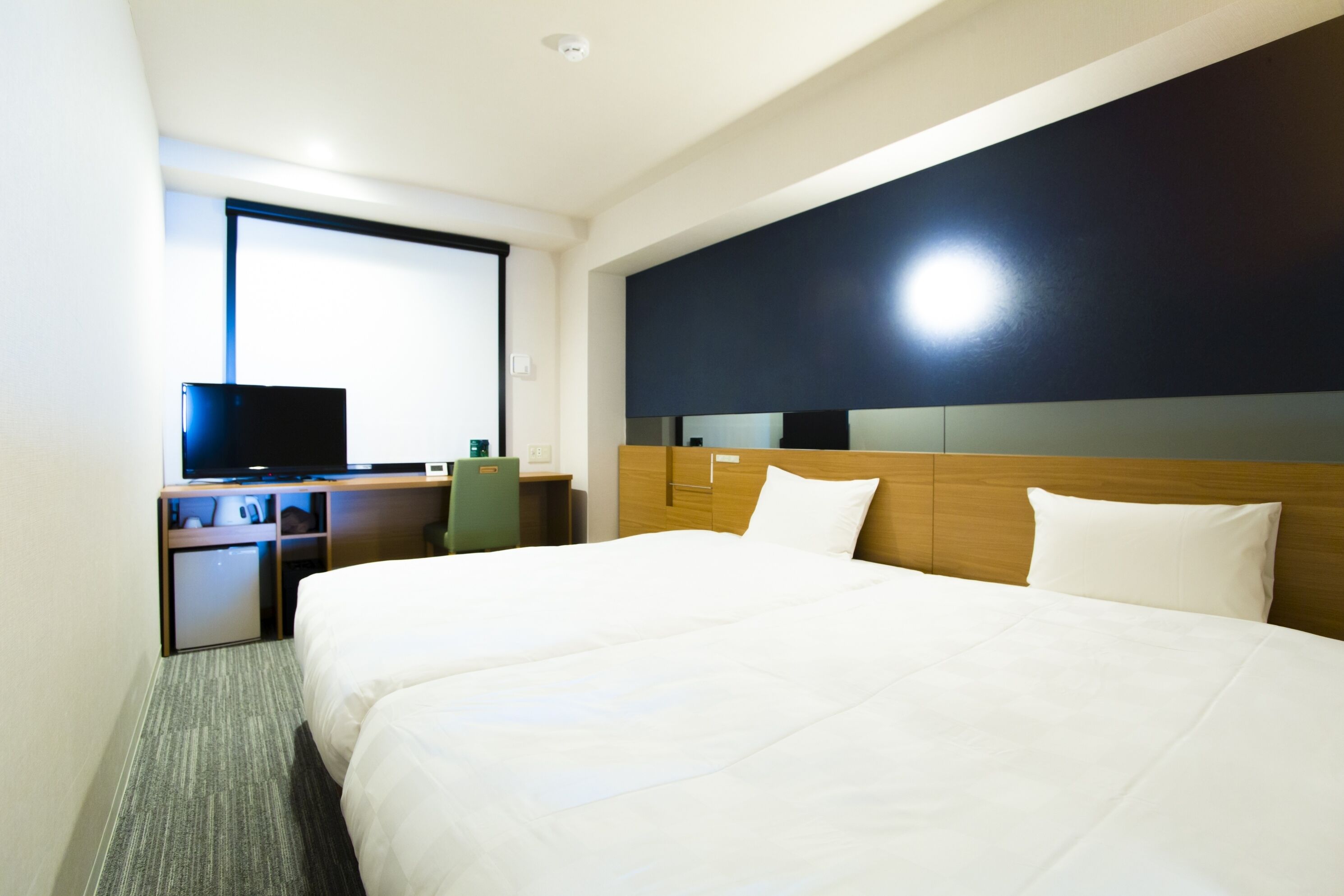 A hotel room with a large bed, a desk with a computer, and a television.