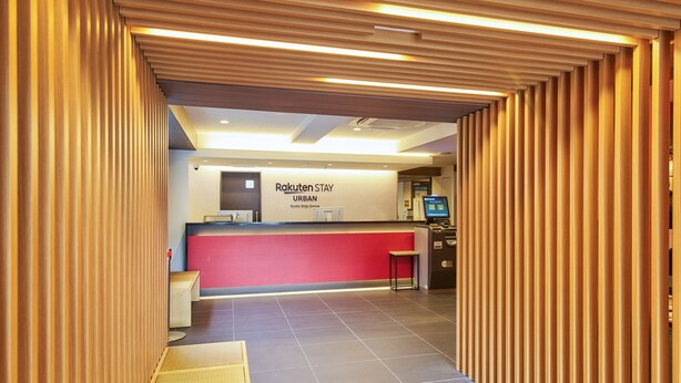A reception area with a red counter, a digital screen, and a wooden partition.