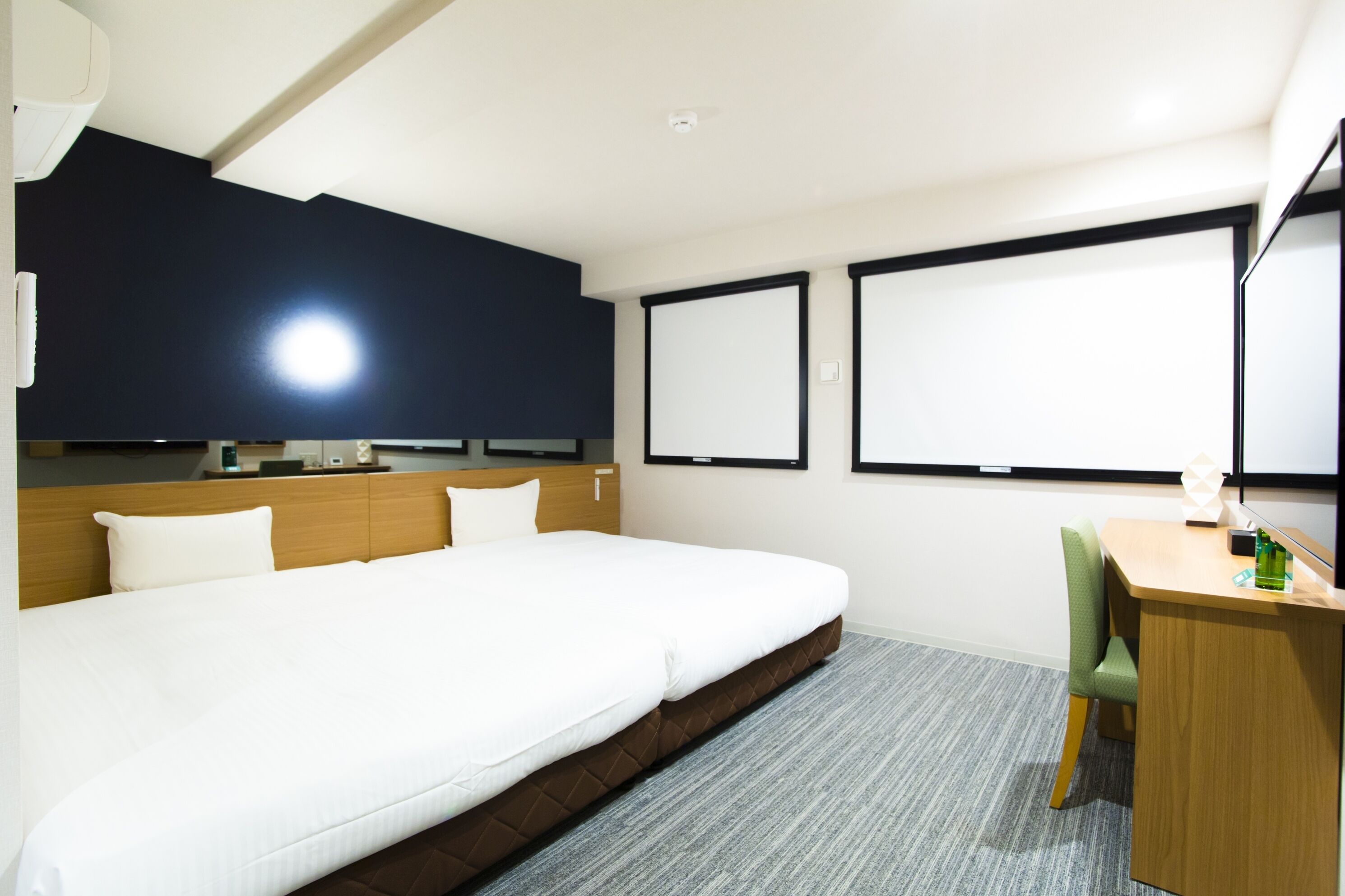 A hotel room with a large bed, a desk, a chair, a flat-screen TV, and a window.