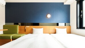 A hotel room with a bed, a green chair, a wooden headboard, and a large window.