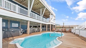 A pool area with a wooden deck, lounge chairs, and a covered seating area. - "Happily Ever After" Luxury Oceanfront home w/ Private Pool, 10 Bedrooms, 10.5 Baths (Holden Beach)