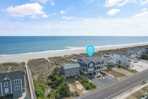 Une zone résidentielle côtière avec des maisons situées près de la plage, un ciel dégagé et une mer calme.