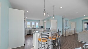 A spacious kitchen with a central island, bar stools, and pendant lighting. - "Happily Ever After" Luxury Oceanfront home w/ Private Pool, 10 Bedrooms, 10.5 Baths (Holden Beach)
