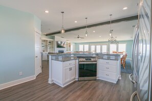 Enjoy cooking in this well-equipped kitchen with a central island, stainless steel range, and white cabinetry.