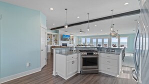 A modern kitchen with a large island, built-in oven, and stainless steel appliances. - "Happily Ever After" Luxury Oceanfront home w/ Private Pool, 10 Bedrooms, 10.5 Baths (Holden Beach)