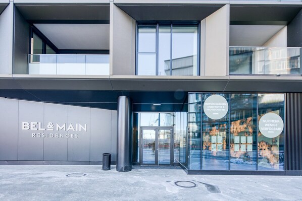 A modern building with a glass facade and a sign for BEL&MAIN RESIDENCES.
