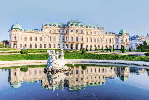 A grand building with a large reflective pool and a statue in the center.