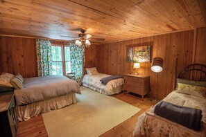 Cozy bedroom with two beds, a nightstand, and a large window.