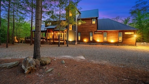 A modern log cabin with a metal roof, surrounded by a forest. - Sunlight Creek in Broken Bow, Sleeps 20! Creekside & Playset (Broken Bow)