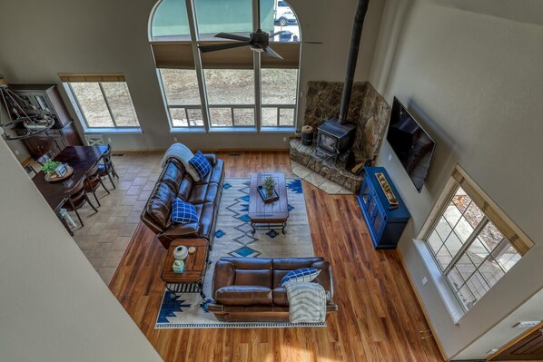 A spacious living room with a stone fireplace, leather sofa, and a dining area with a wooden table and chairs.