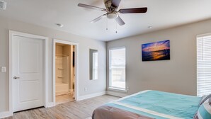 A bedroom with a bed, a ceiling fan, and a painting on the wall. - Milano Guesthouse (Lubbock)