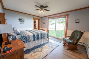 Une chambre à coucher avec un lit, une chaise, un bureau et un ventilateur de plafond.