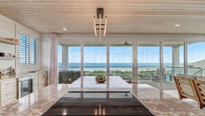 Un'ampia cucina con una grande isola, un'area pranzo con vista sulla spiaggia e un moderno design del soffitto.