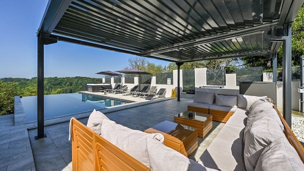 A modern outdoor lounge area with a pool, wooden furniture, and a covered patio. - Stunning Villa with infinity pool, Croatia (Donja Poljana)